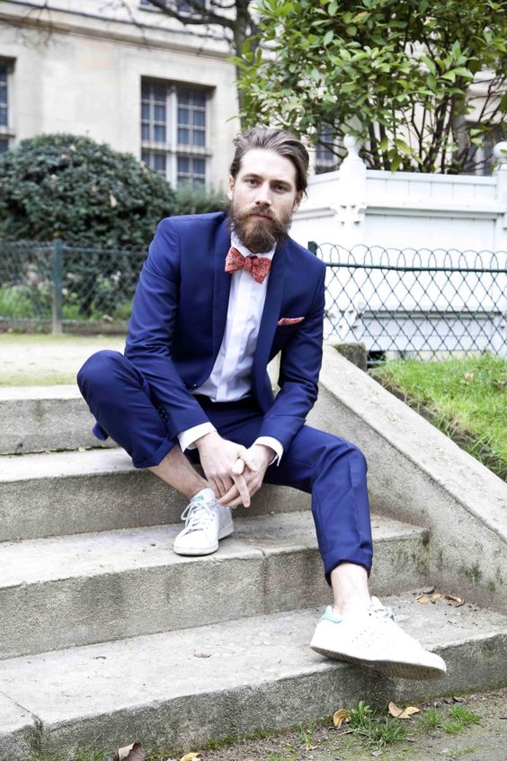 a bright blue wedding suit, no socks, white sneakers and a coral printed bow tie