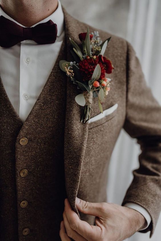 a brown tweed three-piece suit, a white button down, a burgundy velvet bow tie and a matching boutonniere for a stylish fall or winter wedding