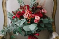 a colorful wedding bouquet of pink and red blooms, foliage and berries plus red ribbons