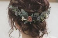a cool and very messy and wavy wedding updo with some locks down and a greenery accent with neutral blooms is amazing for the fall