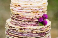 a crepe wedding cake with berry cream and fresh berries and blooms on top feels very summer-like