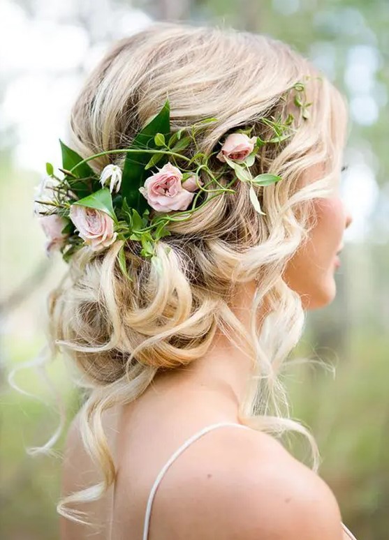 a crown of roses sits a top of a curled bun, with pieces pulled out here and there for an ethereal do