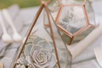 a cute copper terrarium with moss, wildflowers and a pale succulent is a chic and stylish wedding centerpiece idea