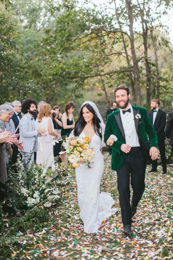a fall groom's look with black pants, a white shirt, an emerald velvet tux with black lapels and black shoes