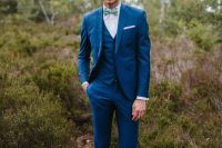 a fashionable look with a bright blue three-piece suit, white sneakers and a bright printed bow tie