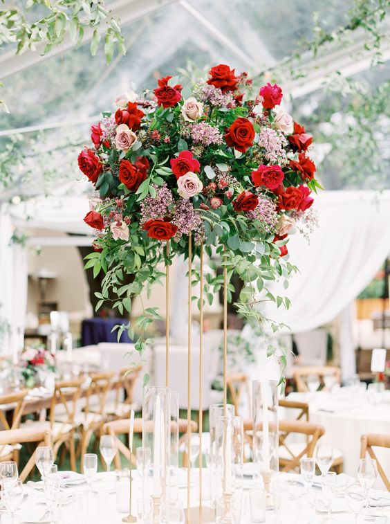 a gorgeous tall wedding centerpiece of pink, blush and red blooms on a gold stand is a fantastic decor idea