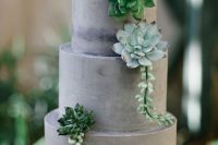 a grey concrete-like wedding cake with plain tiers and succulents for decor is a very chic and modern dessert