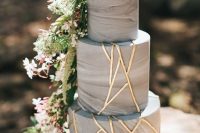 a grey marble cake with gold detailing, cascading blooms and greenery is a bold and chic modern dessert option