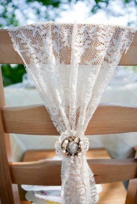 a lace chair cover with a vintage brooch to secure it is a beautiful and chic idea for a vintage-inspired wedding