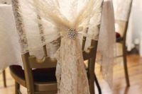 a lace wedding chair cover up with a vintage brooch is a stylish and pretty idea for a wedding, it will add a slight vintage feel to the space