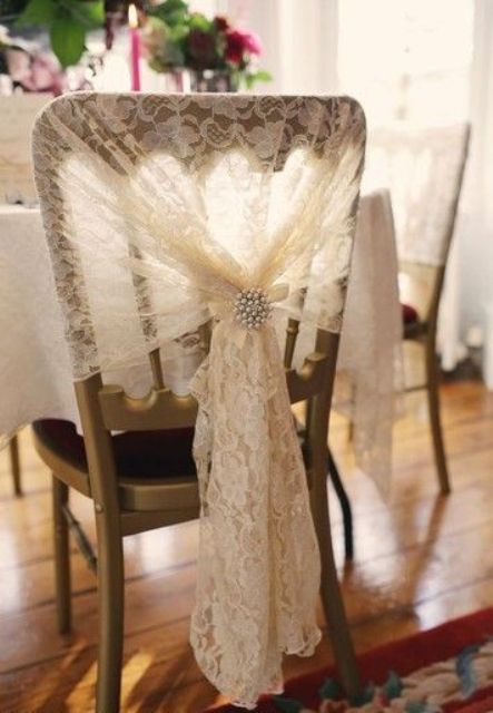 a lace wedding chair cover up with a vintage brooch is a stylish and pretty idea for a wedding, it will add a slight vintage feel to the space