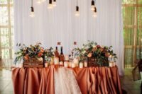 a layered orange tablecloth plus lace, candles on the table and floor, crates with blooms and bulbs over the table