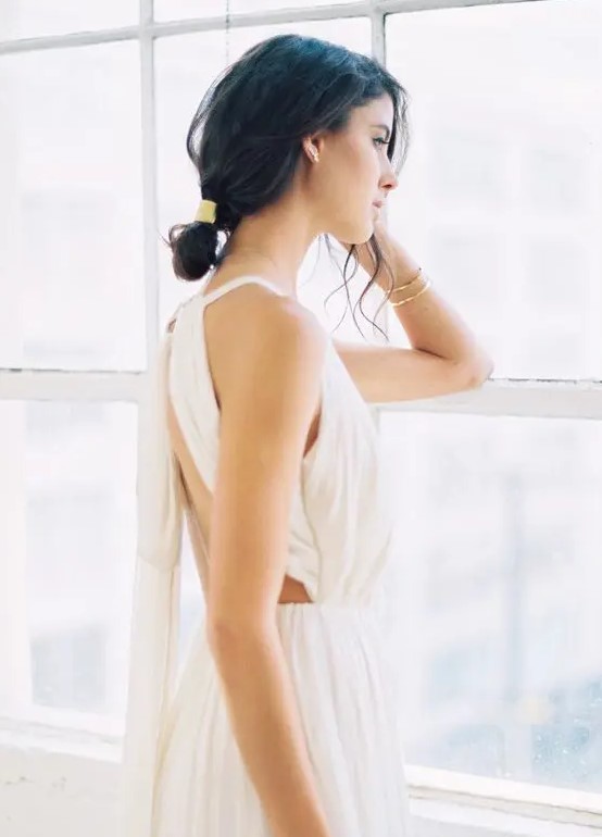 a messy low bun with bangs and a shiny accessory for a cool modern look at a destination wedding