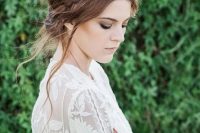 a messy updo with a loose halo braid on top and some locks down for a boho bride