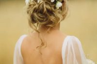 a messy wavy updo with fresh white flowers and some locks down is a cool idea to rock for a romantic bride