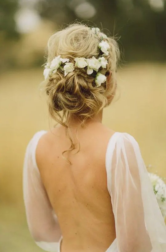 a messy wavy updo with fresh white flowers and some locks down is a cool idea to rock for a romantic bride