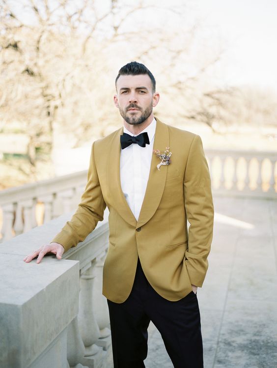 a mustard tux, a white shirt, black bow tie and a dried bloom boutonniere for a bright summer or fall outfit
