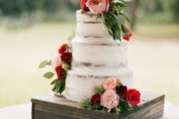 a naked wedding cake decorated with pink and red blooms and greenery is a chic and cool idea to rock in winter