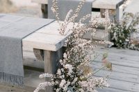 a natural wedding ceremony space with wooden benches covered with grey wool and neutral lush blooms