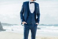 a navy three-piece suit with a dinner jacket, a black bow tie and white sneakers for a modern touch