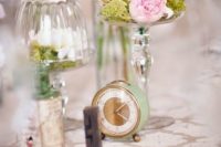 a pastel wedding centerpiece with pink blooms, moss and a small green clock for a vintage wedding