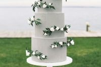 a plain grey wedding cake with white blooms and greenery is a chic and modern idea with a touch of romance