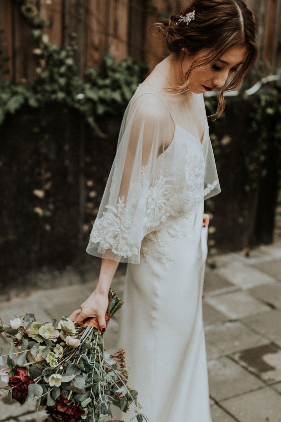 a plain slip wedding dress paired with a delicate and elegant capelet with a lace trim are an amazing combo for a romantic bridal look