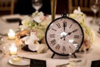 a refined and chic wedding centerpiece with white and pastel blooms, a large candelabra and a large clock
