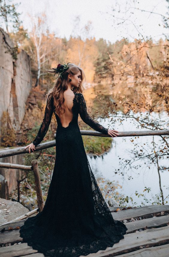 a refined black lace A-line wedding dress with a cutout back, long sleeves and a train plus black earrings for a Halloween wedding
