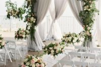 a refined ceremony space with grey curtains, pastel and neutral blooms and greenery is a chic option to go for