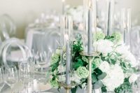 a refined grey wedding tablescape with neutral blooms and greenery and tall grey candles and a tablecloth