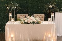 a sequin tablecloth, a greenery runner, candles, a floral centerpiece with some foliage for a touch of glam
