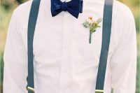 a simple summer outfit with tan pants, blue suspenders, a navy velvet bow tie and a bright boutonniere