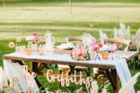 a sweetheart table decorated with greenery, blooms and dried herbs plus candles and florals and a calligraphy sign