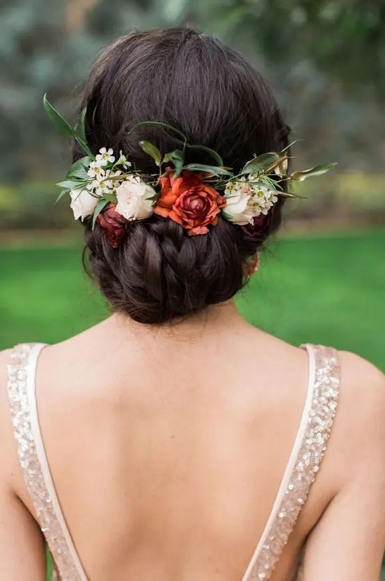a tight braided low updo with foliage and fall flowers is a great idea for a destination wedding and is comfy in wearing