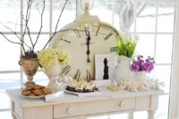 a vintage wedding sweets table with bright and white blooms and an oversized clock for decor