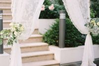 a wedding entrance done with lace curtains, white blooms and greenery is a gorgeous solution for a wedding
