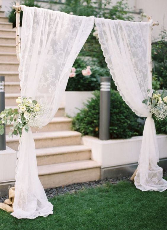 a wedding entrance done with lace curtains, white blooms and greenery is a gorgeous solution for a wedding