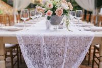 a wihte lace rable runner is a nice alternative to a usual wedding tablecloth and it will add a chic and refined feel to the space
