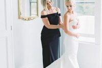 an elegant black fitting off the shoulder dress with an oversized bow is very chic and bold for a mother of the bride