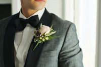 an elegant grey tux with black lapels and a black bow tie plus a neutral floral boutonniere for summer or fall