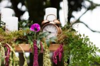 an overhead wedding decoration – a shelf with pillar candle, cascading greenery and pink blooms plus a clock
