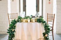 oversized candle lanterns, a greenery and white bloom table runner and some candles on the table