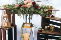 oversized candle lanterns, crates with blooms and greenery and a greenery and floral table runner
