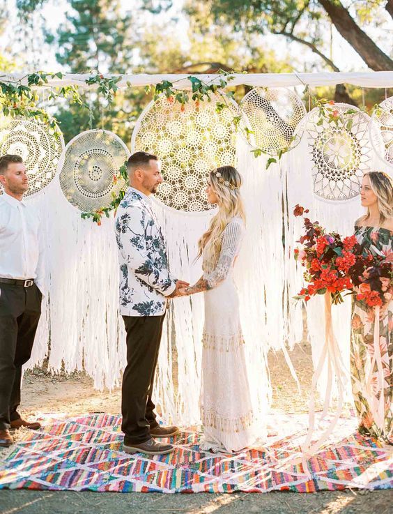 oversized lace embroidery hoops as a wedding backdrop, greenery and blooms, a colorful rug are a great idea for a boho wedding