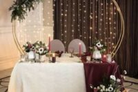 white blooms on the floor, candles, a lush and moody floral arrangement and the wedding arch with lights
