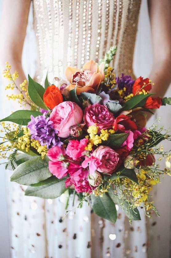 a bold wedding bouquet with pink, pirple, orange and yellow blooms and foliage for a bright summer wedding