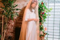 a bride rocking a neutral wedding dress, a bright floral crown and an orange veil with fringe looks wow