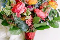 a bright summer wedding bouquet with pink, yellow, purple and blue flowers and greenery for a refined summer wedding