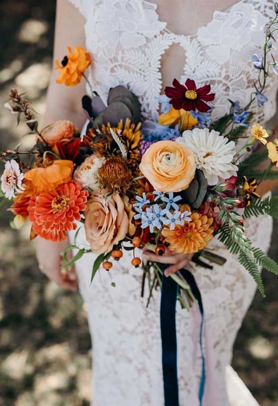 a bright wedding bouquet of orange, rust, blue, red, burgundy, purple, berry and greenery is amazing for a wedding with pops of color